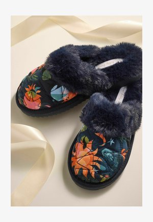 Tükkide ümber käivad tumesinised edasi-tagasi libisemisjalatsid, millel on värvikad lillemustrid ja pehme kunstkarusnahast äär. Tekstuuriga tald, mis tagab parema haarde.