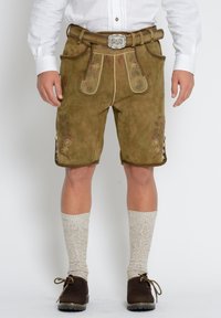 Bruna mockalederhosen med blommönsterbroderi, hög midja och knapppdetaljer. Matchat med knähöga texturerade strumpor och mörka skor.