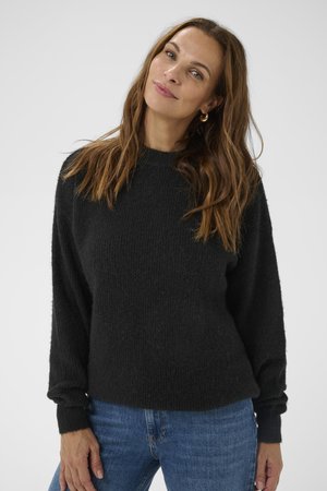 Schwarzer Wollmischpullover mit strukturierter Oberfläche, rundem Halsausschnitt und langen, leicht gepufften Ärmeln. Getragen mit blauen Jeans.