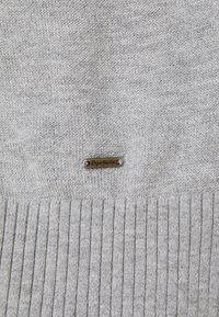 Hellgrauer gestrickter Pullover mit einem gerippten Saum. Zeigt ein kleines Metallschild mit der Aufschrift "Pepe Jeans", das am Stoff befestigt ist.
