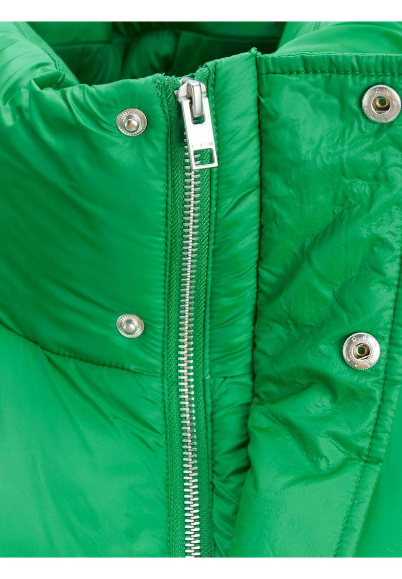 Giacca a vento verde con finitura lucida, dotata di zip argentata e bottoni a pressione. Il tessuto è imbottito con una texture morbida e trapuntata.