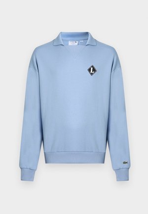 Felpa azzurro chiaro con scollo a V, collo a coste, maniche lunghe e toppa con logo a diamante nero sul petto. Polsini e orlo a coste.