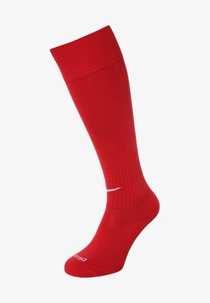 Red knee-high socks with a ribbed texture, featuring white branding near the ankle and a snug fit at the top.