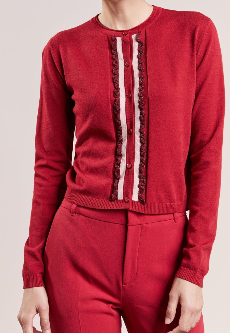 Cardigan rouge avec panneau avant texturé et froncé, fermeture à boutons. Présente des rayures verticales contrastantes et des poignets côtelés.