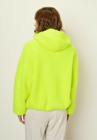 Neon yellow fleece hoodie with a relaxed fit, large hood, and soft texture, featuring dropped shoulders and long sleeves.