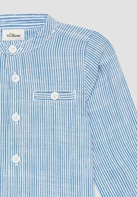 Blauw en wit gestreept knoopshirt met een ronde kraag. Heeft een borstzak en witte knopen. Gemaakt van lichte stof.