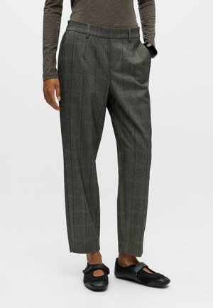 Grijze geruite broeken met een hoge taille, rechte pijpen en een zachte textuur. Gekleed met zwarte platte schoenen met een strikaccent.
