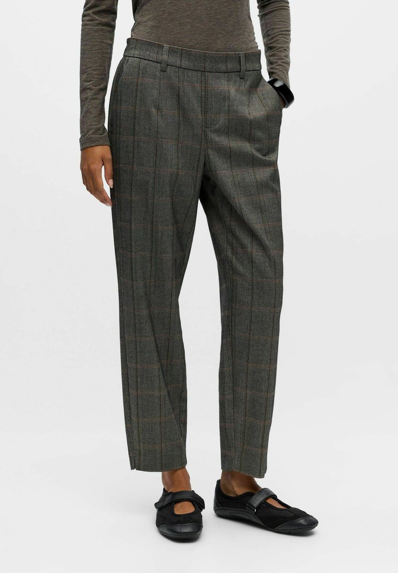Pantalons à carreaux gris avec une taille haute, des jambes droites et une texture douce. Portés avec des chaussures plates noires ornées d'un nœud.