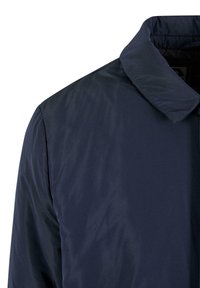 Marineblaue Jacke mit einer glatten, matten Textur, ausgestattet mit einem spitzen Kragen und einem minimalistischen Design ohne sichtbare Verschlüsse oder Muster.