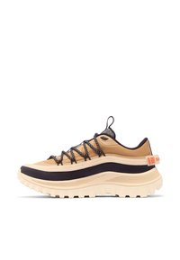 Baskets de randonnée beige et noir avec une semelle épaisse à rainures, des lacets noir et blanc, et un onglet orange au talon, présentées sur fond blanc.