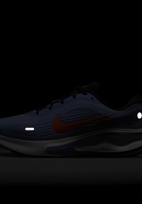 Běžecká obuv Nike v modrém textilu s oranžovým logem Swoosh. Disponuje polstrovanou podrážkou, černými akcenty a texturovaným designem svršku.