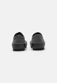 Sapatos de tecido cinza com superior texturizado, sola em borracha e um leve tacão. O design bicolor apresenta detalhes cosidos na parte de trás.