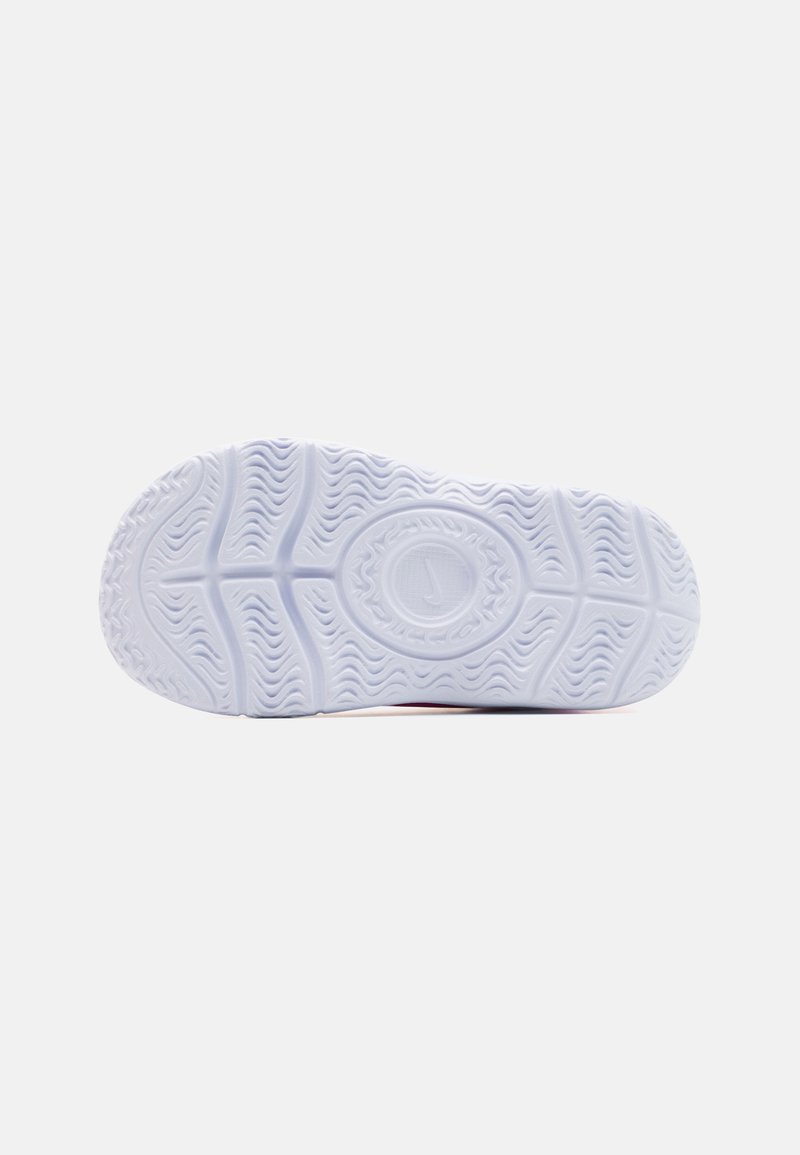 Semelle de chaussure en caoutchouc blanc avec des motifs texturés et des lignes courbes, ornée d'un logo circulaire au centre. Fini en matériau lisse et durable.