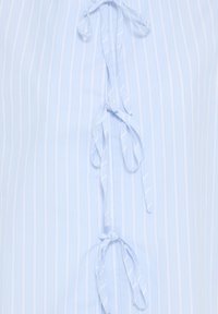 Tissu bleu clair avec des rayures blanches verticales, avec trois nœuds attachés alignés verticalement au centre.