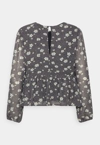 Blusa de manga longa em tecido preto transparente, com um padrão floral de flores brancas e azuis, com bainha peplum e costas com abertura em forma de lágrima.