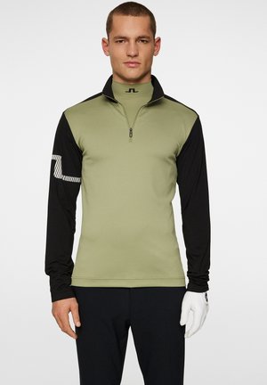 Maglione fitted a maniche lunghe con mezza zip. Corpo verde oliva, maniche nere, tessuto testurizzato e logo a strisce bianche sul braccio sinistro.