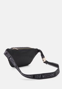 Černá ledvinka z hladkého materiálu, s zlatým zipem, šikmým tvarem a popruhem s nápisem "LOVE MOSCHINO" v bílé a šedé barvě.