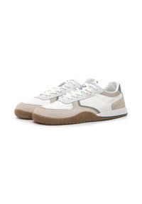 Par de zapatillas bajas blancas y beige con suela de goma y diseño con cordones, colocadas lado a lado sobre un fondo blanco.
