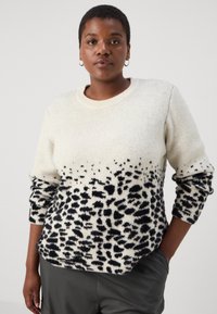 Přesně padnoucí pletený svetr v krémové barvě s černým leopardím potiskem na spodní části. Má kulatý výstřih a ohrnuté manžety, jemnou strukturu a uvolněný střih.