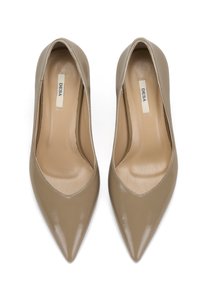 Beige lackleder High Heels mit zulaufender Spitze, offenen Seiten und einer glatten, glänzenden Oberfläche. Das Innere ist mit einer hellen Fütterung ausgestattet.