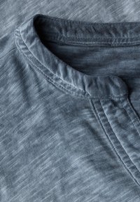 T-shirt blu con effetto melange, colletto rotondo, texture morbida e dettagli cuciti lungo il colletto e le cuciture laterali.