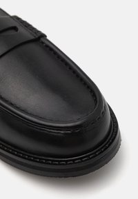 Mustat nahka loaferit, joissa on sileä pinta, pyöreä kärki, koristeellinen ommel ja matala kumipohja.