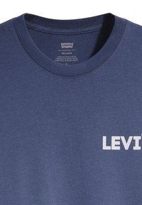 Marineblauwe katoenen t-shirt met een ronde hals en wit "LEVI'S" logo aan de linkerkant. Gladde textuur en relaxte pasvorm.