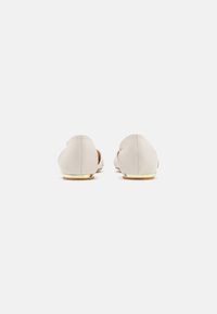 Balerini bej din piele, cu un finisaj neted, vârf rotund și un mic accent auriu pe toc. Design minimalist cu o formă clasică.