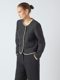 Giacca nera intrecciata con una finitura testurizzata, rifiniture crema lungo il collo e le tasche, e una vestibilità strutturata. Abbinata a pantaloni neri.