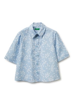 Jasnoniebieska koszula z krótkim rękawem i guzikami, z białym kwiatowym wzorem i spiczastym kołnierzem, ułożona na białym tle.