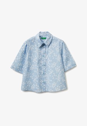 Jasnoniebieska koszula z krótkim rękawem i guzikami, z białym kwiatowym wzorem i spiczastym kołnierzem, ułożona na białym tle.