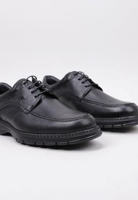 Scarpe da uomo in pelle nera con punta arrotondata, cuciture decorative e design con lacci. Presentano una finitura texturizzata e suola in gomma per una buona aderenza.