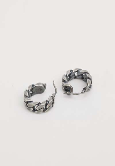 Boucles d'oreilles en argent en forme de créole avec un design tressé, présentant une surface texturée et un fermoir sécurisé. Chaque boucle d'oreille a une forme circulaire.