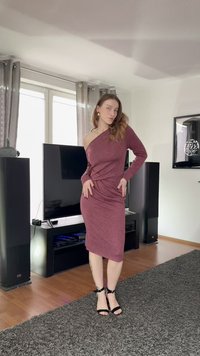 Dopasowana, bordowa sukienka na jedno ramię wykonana z miękkiego materiału, z efektownym skręceniem w talii. Noszona z czarnymi szpilkami na kostkę z paskiem.