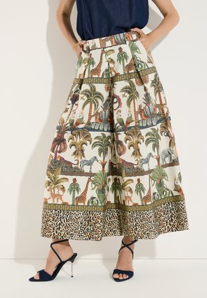 Weit geschnittene Hose mit Safari-Tier- und Palmenmuster, Leopardenbordüre, getragen mit dunkelblauen, hochhackigen Sandalen mit Riemchen.