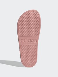 Podošva ružovej gumenej obuvi s textúrovaným diamantovým vzorom a vyrazeným logom "adidas". Zakrivený tvar s hladkým povrchom.