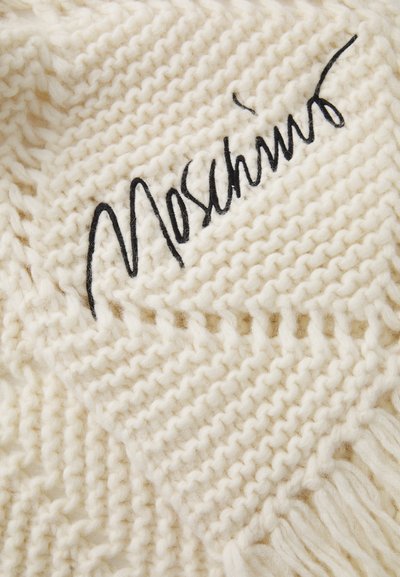 Kootud koorevalge pleed, millel on silmatorkav must tikitud "Moschino" logo, friteeritud servade ja tekstuurse mustriga.