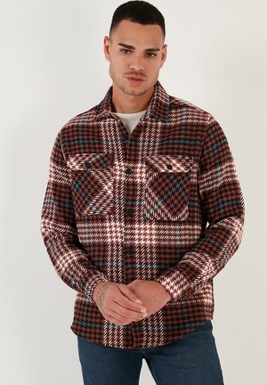 Red and black plaid flannel shirt with white and blue accents, featuring a button-up front, two chest pockets, and a collar.