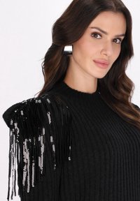 Schwarzer gerippter Pullover aus strukturiertem Stoff mit metallischen Fransen an den Schultern. Ein subtiler Glanz von Pailletten verstärkt die Eleganz.