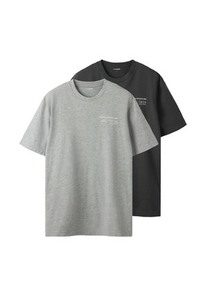 Két kereknyakú póló, egy szürke és egy fekete, puha pamutból készült. Mindkettőn egy apró fehér logó található az elülső bal oldalon.