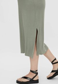 Olive green midi dress with side slits. Soft material, relaxed fit. Black strappy sandals with a flat sole and ankle strap.