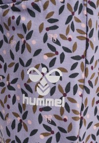 Lila tyg med ett blommönster som har gröna blad och bäraccenter. Inkluderar en vit logotyp "hummel" längst ner.