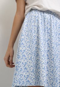 Sininen kukkakuvioinen hame, jossa valkoinen lehtikuvio, joustava vyötärönauha ja pehmeä puuvillainen materiaali, pituus puoliväliin pohjetta.