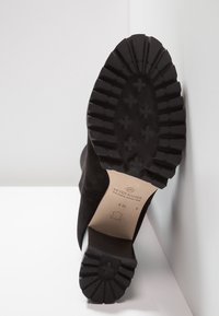 Semelle de botte en cuir noir avec des rainures profondes et un talon, affichée verticalement montrant la marque "Peter Kaiser" et les indications de taille sur la semelle intérieure.