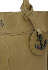 Borsa in pelle verde oliva con dettagli cuciti, dotata di un ciondolo a forma di ancorina attaccato da un anello e un piccolo logo ad ancora impresso sul lato.