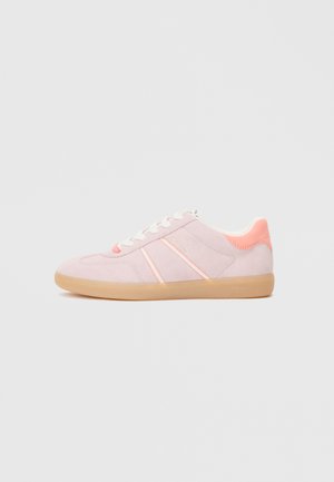 Light pink suede sneakers with white laces, orange accents, and a gum rubber sole. Features a smooth texture and simple design.