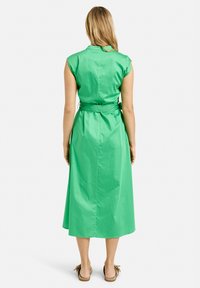 Grünes, ärmelloses Midi-Kleid mit tailliertem Gürtel, Kragen, glatter Textur und schlichten Design, von hinten betrachtet.