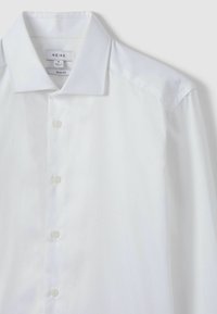 Weißes Hemd aus glattem, leichtem Stoff. Mit klassischem Kragen, Knopfverschluss und langen Ärmeln mit kontrastierenden Schulterpaneelen.