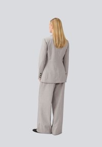 Grey pinstriped suit with a tailored blazer and wide-leg trousers. Smooth texture with buttons on the cuffs, viewed from the back.