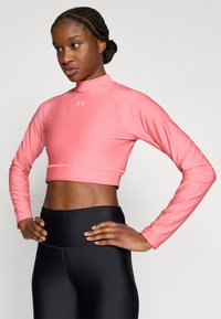 Εφαρμοστό crop top με μακριά μανίκια σε φωτεινό ροζ χρώμα, κατασκευασμένο από λείο συνθετικό ύφασμα, με ψηλό γιακά και λεπτομέρειες σε αντίθετη ραφή.